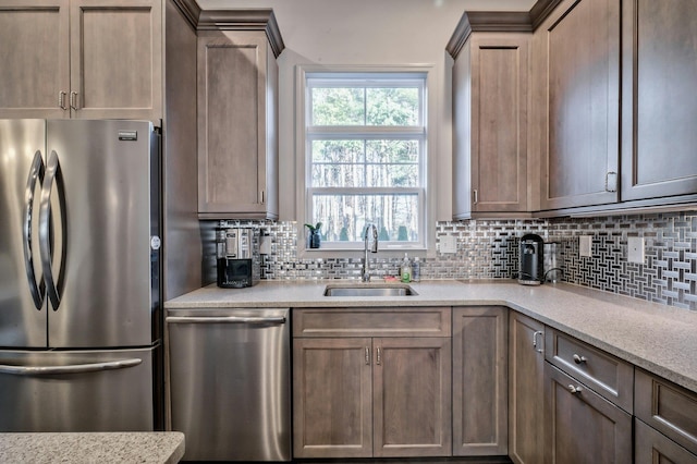 kitchen featuring stainless steel appliances, sink, tasteful backsplash, and light stone counters