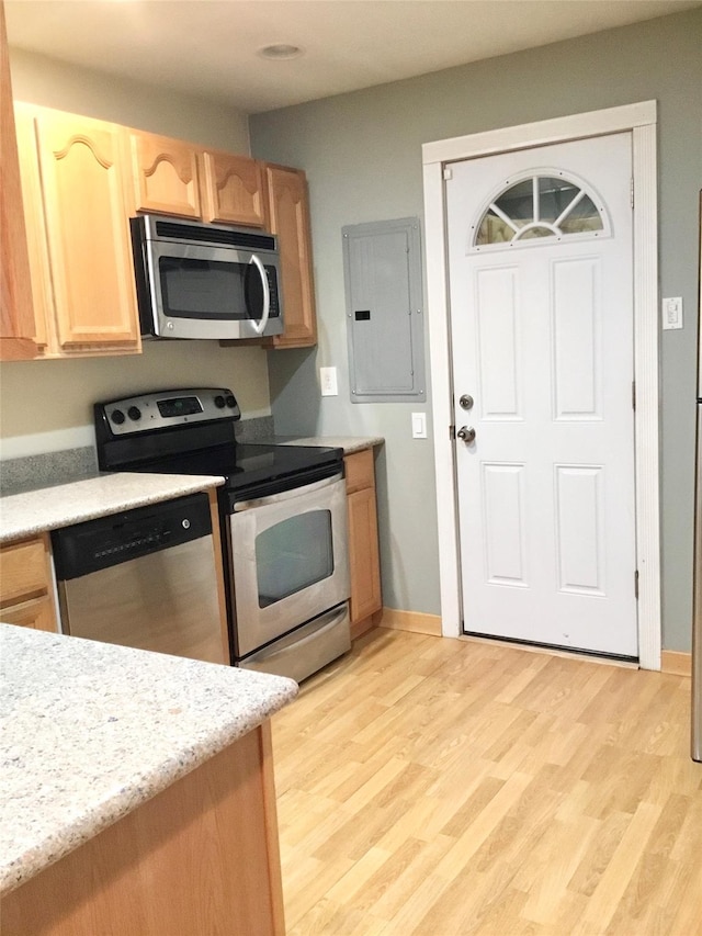 kitchen with electric panel, stainless steel appliances, light wood-type flooring, and light brown cabinets