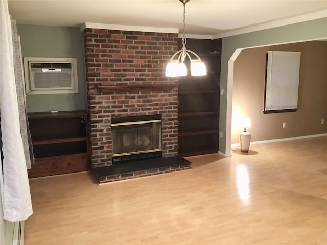 unfurnished living room with a brick fireplace, hardwood / wood-style floors, ornamental molding, and a wall unit AC