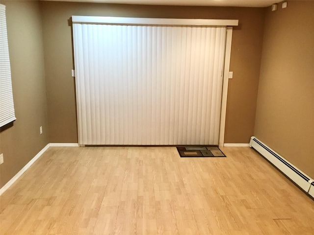 empty room featuring light hardwood / wood-style flooring and a baseboard heating unit