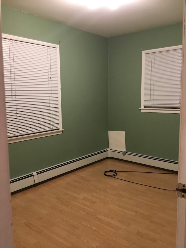 empty room featuring baseboard heating and light hardwood / wood-style floors