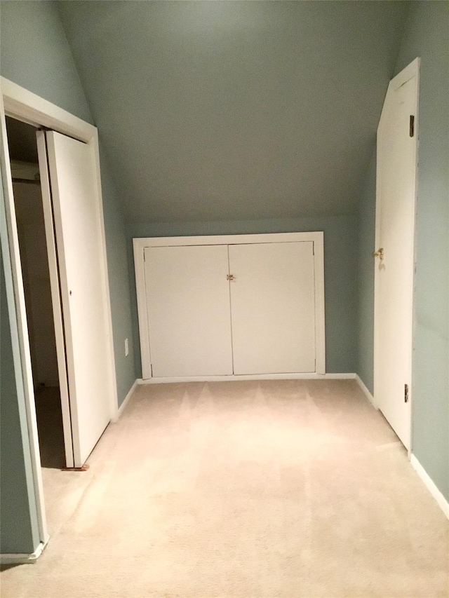 unfurnished bedroom featuring light colored carpet, vaulted ceiling, and a closet