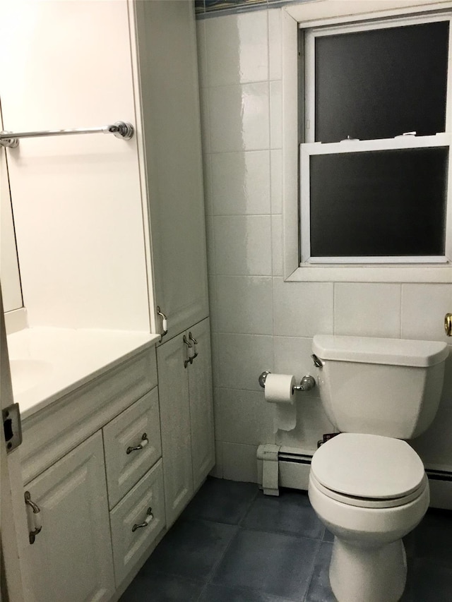 bathroom with tile walls, baseboard heating, toilet, and vanity