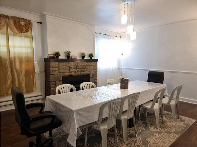 dining area with ornamental molding, dark hardwood / wood-style flooring, and a stone fireplace