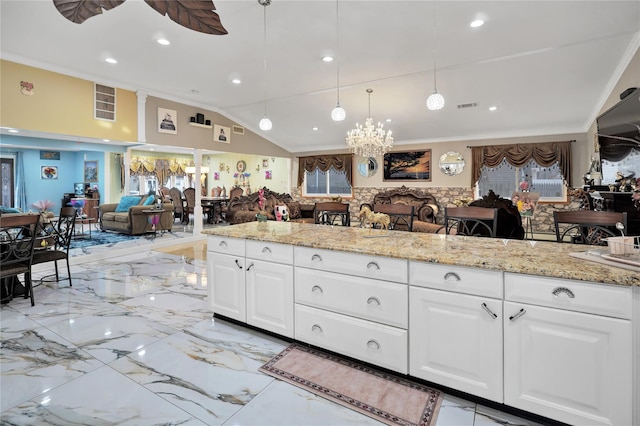 kitchen with white cabinetry, vaulted ceiling, ornamental molding, ceiling fan with notable chandelier, and light stone counters