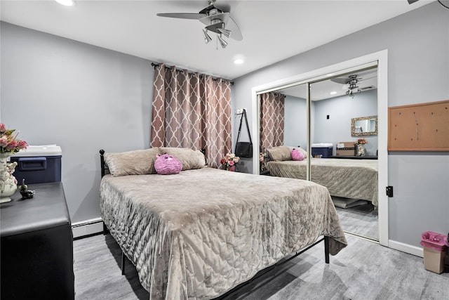 bedroom featuring a baseboard heating unit, a closet, light wood-type flooring, and ceiling fan