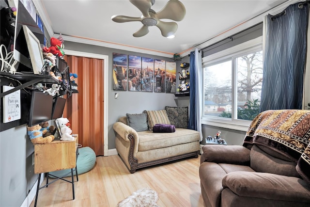 living area with ceiling fan, plenty of natural light, crown molding, and hardwood / wood-style floors