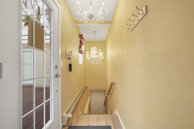 stairway with baseboard heating and a notable chandelier