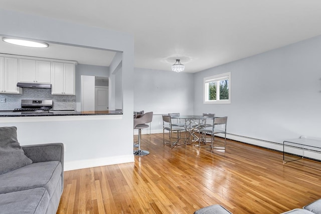 kitchen featuring stainless steel range oven, tasteful backsplash, an inviting chandelier, light wood-type flooring, and white cabinets