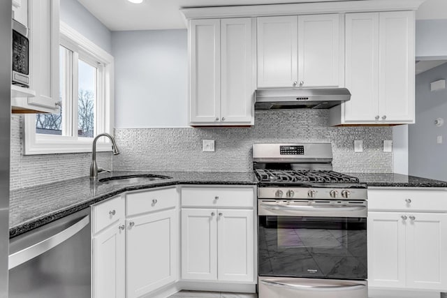 kitchen featuring stainless steel appliances, white cabinets, sink, and dark stone counters