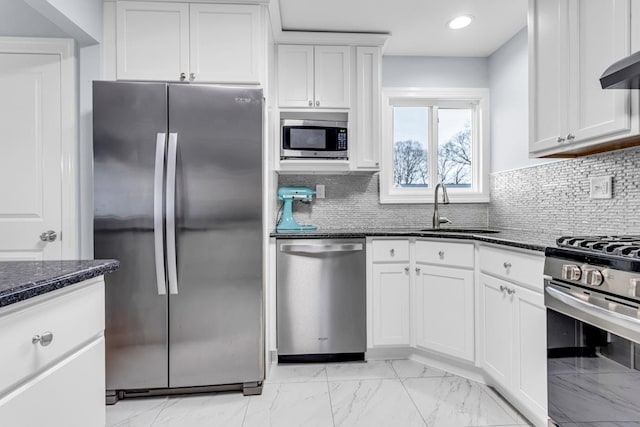 kitchen with white cabinets, stainless steel appliances, dark stone counters, sink, and tasteful backsplash