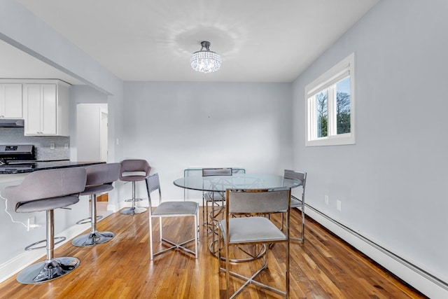 dining room with a baseboard heating unit, light hardwood / wood-style floors, and a chandelier