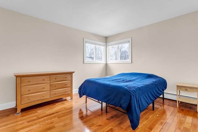 bedroom featuring a baseboard heating unit and light hardwood / wood-style floors