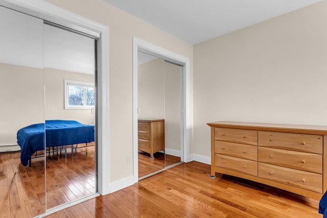 bedroom featuring light hardwood / wood-style flooring, a closet, and a baseboard heating unit