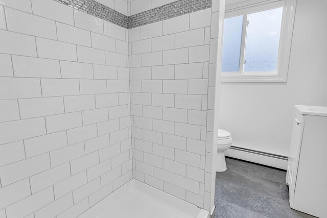 bathroom with toilet, a tile shower, and a baseboard radiator