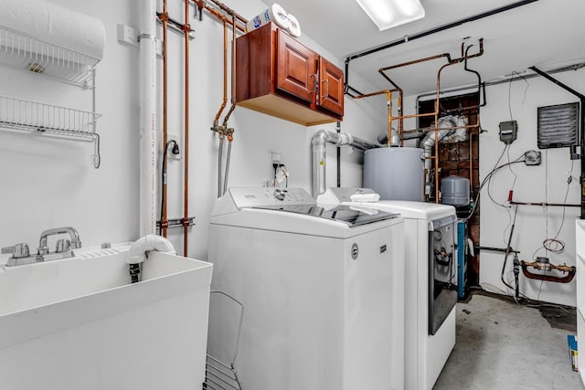 clothes washing area featuring sink, cabinets, washer and clothes dryer, and gas water heater