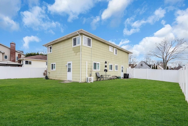 back of property with ac unit and a yard