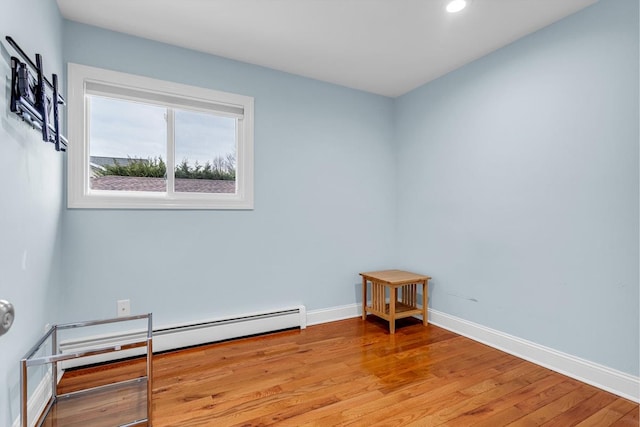 spare room featuring baseboard heating and light hardwood / wood-style flooring