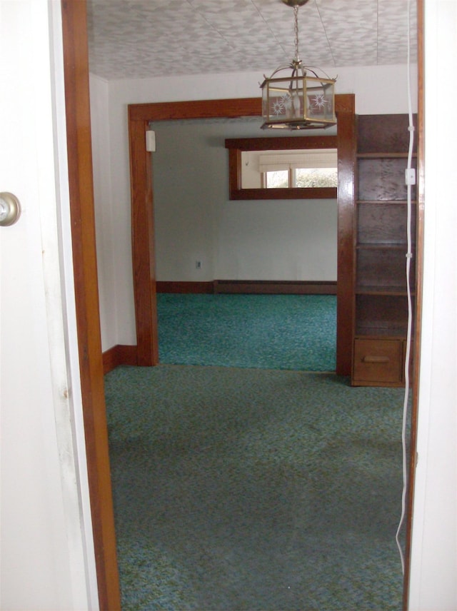 corridor with carpet flooring, a textured ceiling, and a chandelier