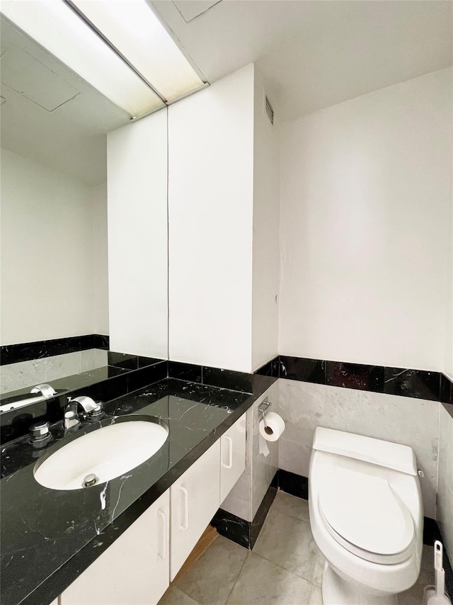 bathroom featuring tile walls, tile patterned flooring, toilet, and vanity