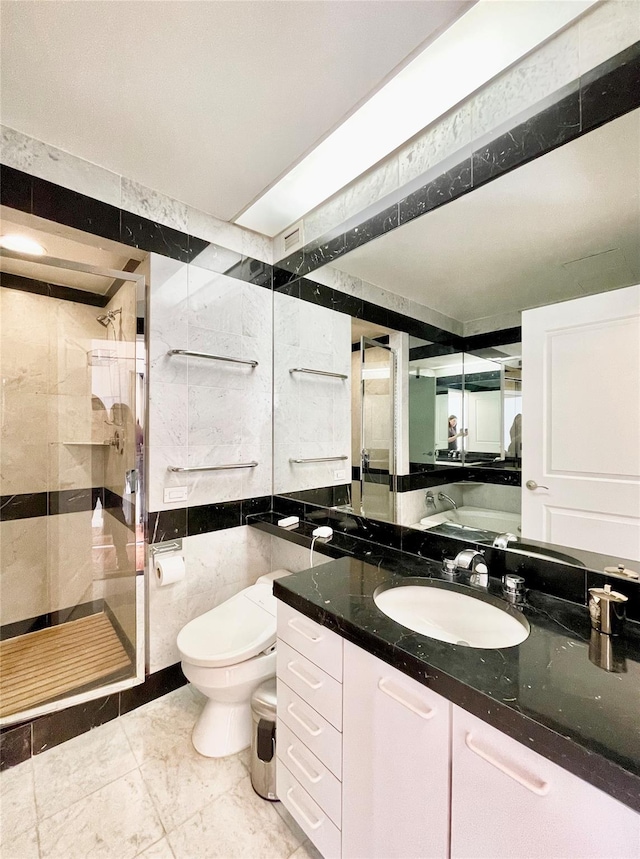 bathroom with vanity, toilet, tiled shower, and tile walls