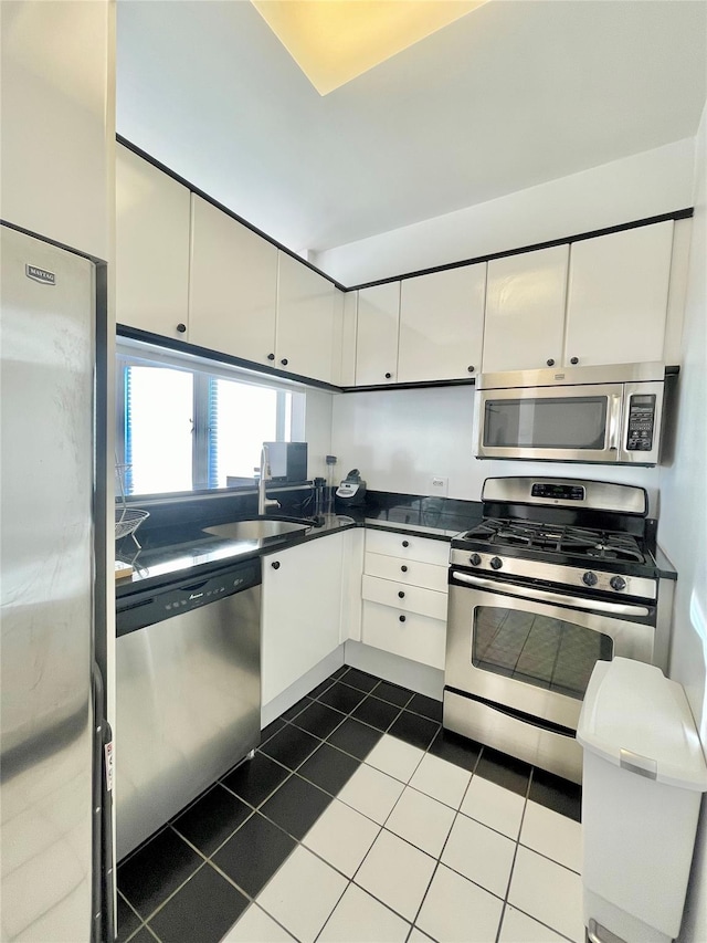 kitchen with stainless steel appliances, dark tile patterned flooring, white cabinets, and sink