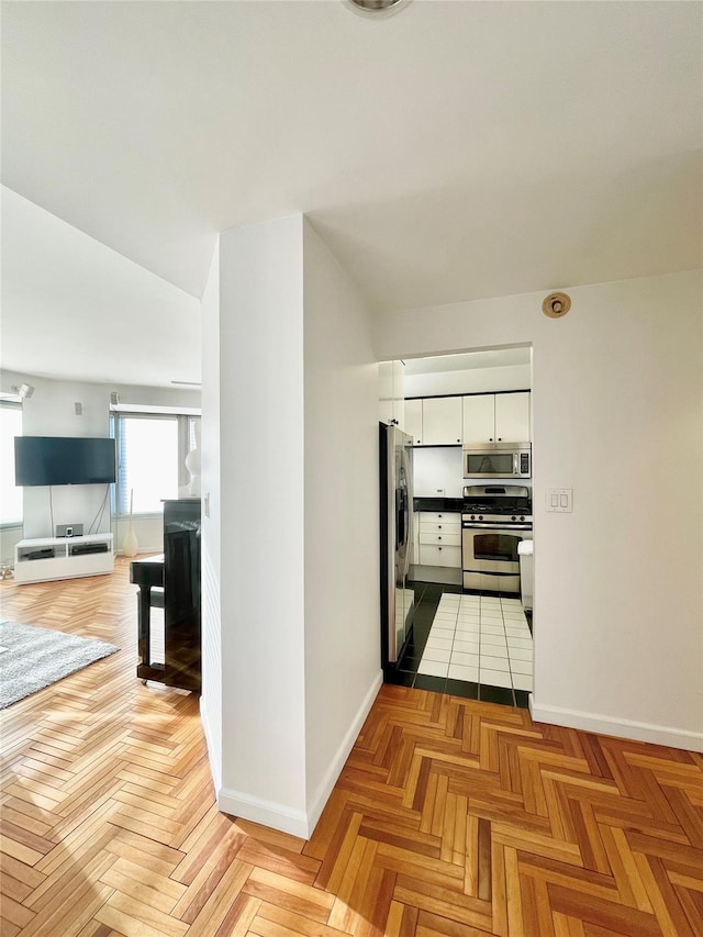 kitchen with appliances with stainless steel finishes, light parquet floors, and white cabinetry