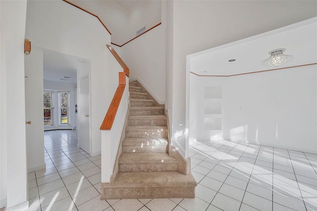 stairs with a high ceiling and tile patterned floors