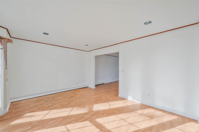 unfurnished room with a baseboard heating unit, ornamental molding, light wood-style flooring, and baseboards