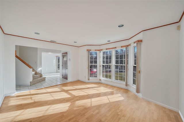 spare room with crown molding, stairs, baseboards, and wood finished floors