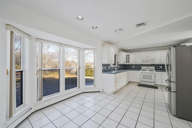 kitchen with visible vents, backsplash, light tile patterned flooring, a sink, and white appliances