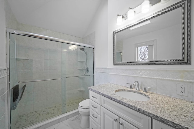 full bathroom with marble finish floor, a wainscoted wall, lofted ceiling, toilet, and a stall shower