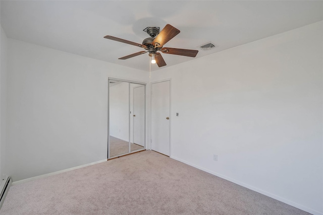 unfurnished bedroom featuring carpet, visible vents, baseboard heating, and baseboards