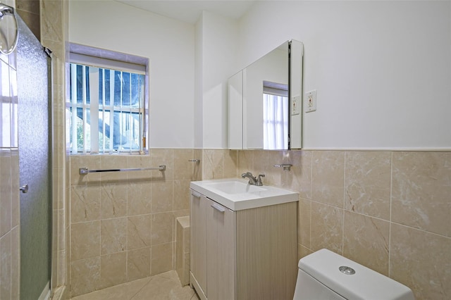 bathroom with wainscoting, toilet, an enclosed shower, vanity, and tile walls