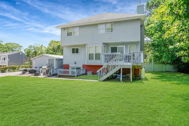 back of property featuring a lawn, a chimney, stairs, fence, and a wooden deck