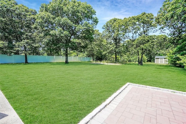 view of yard featuring fence, a patio, an outdoor structure, and a storage shed