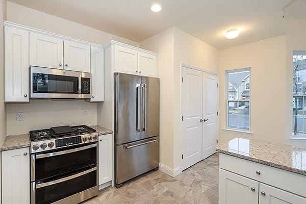 kitchen with light stone countertops, white cabinets, and appliances with stainless steel finishes