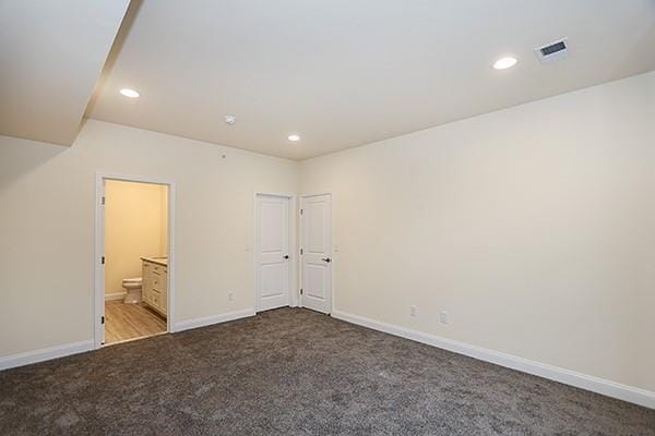 unfurnished bedroom featuring light carpet and connected bathroom