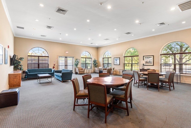 carpeted dining area with a wealth of natural light and crown molding