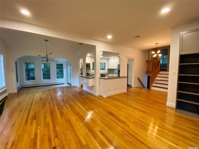 unfurnished living room featuring a baseboard radiator, light hardwood / wood-style floors, and a notable chandelier