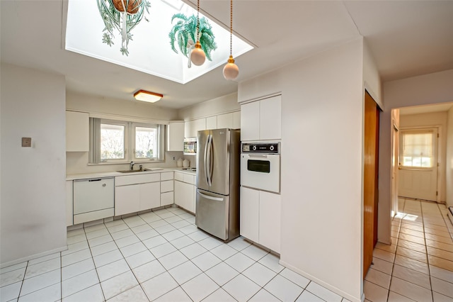 kitchen with stainless steel appliances, white cabinetry, sink, and light tile patterned floors