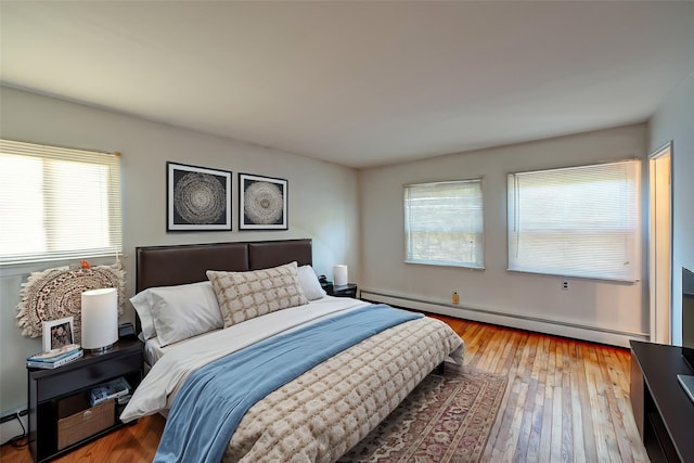 bedroom with light hardwood / wood-style flooring and baseboard heating