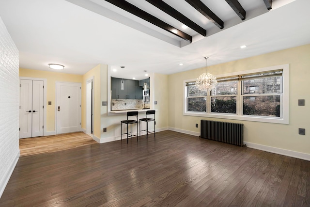 unfurnished living room with dark hardwood / wood-style floors, radiator, beamed ceiling, and an inviting chandelier