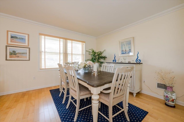 dining space featuring light wood-type flooring and crown molding