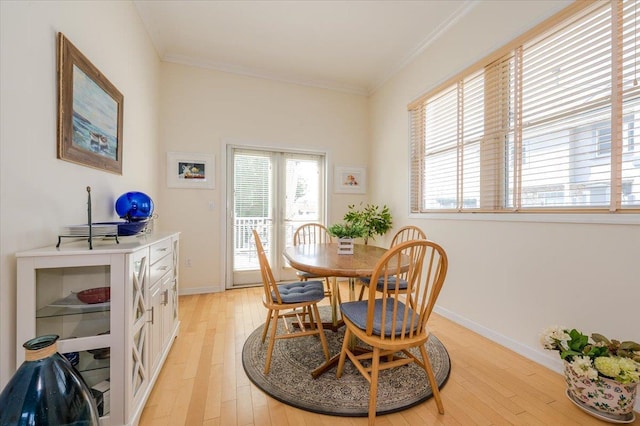 dining area with ornamental molding and light hardwood / wood-style flooring