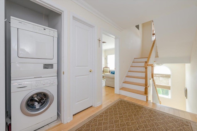 laundry room featuring stacked washer / dryer, crown molding, and hardwood / wood-style flooring