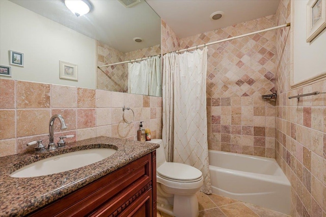 full bathroom featuring tile patterned flooring, vanity, tile walls, toilet, and shower / bath combo