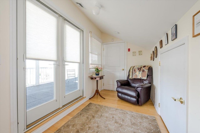 sitting room with a wealth of natural light, lofted ceiling, and hardwood / wood-style floors