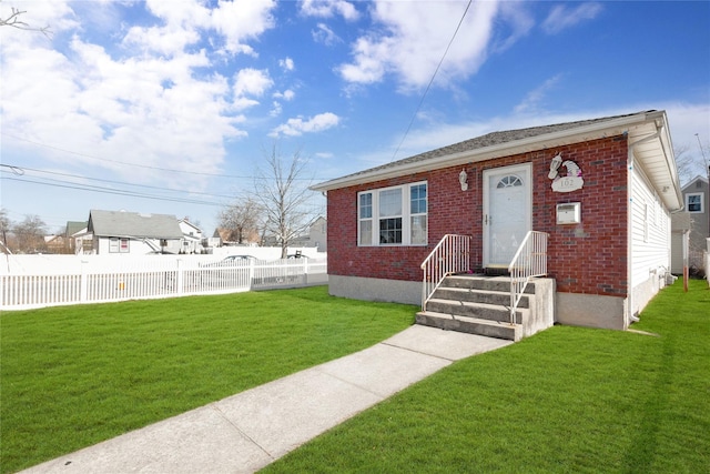 view of front facade with brick siding, a front yard, and fence