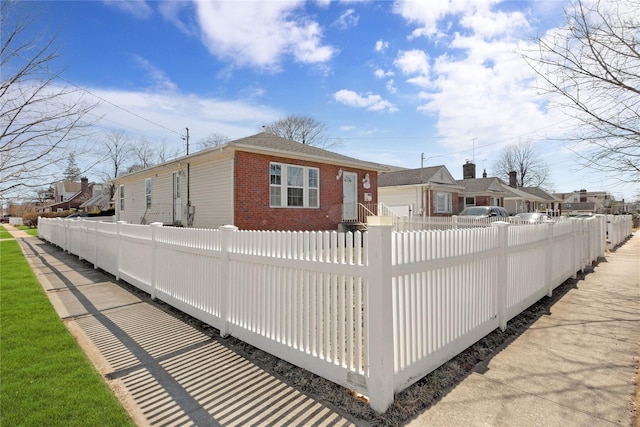 exterior space with brick siding, a residential view, and a fenced front yard